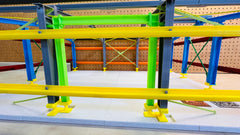 View through the sidewall of the PEMB Training Model, with lime-green and gray columns, yellow girts and the X-braced far wall behind.